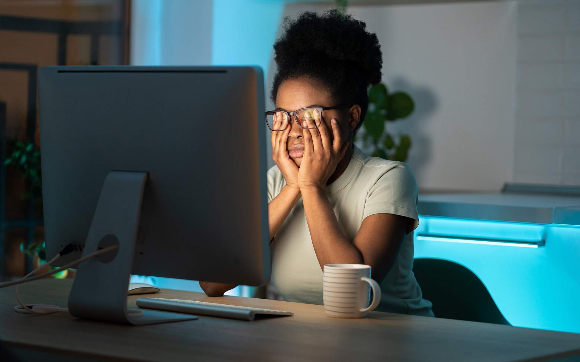 Symptoms of overworking. Young tired overworked african woman freelancer in eyeglasses working late from home, sitting in front of monitor, feeling eye strain and fatigue during computer work