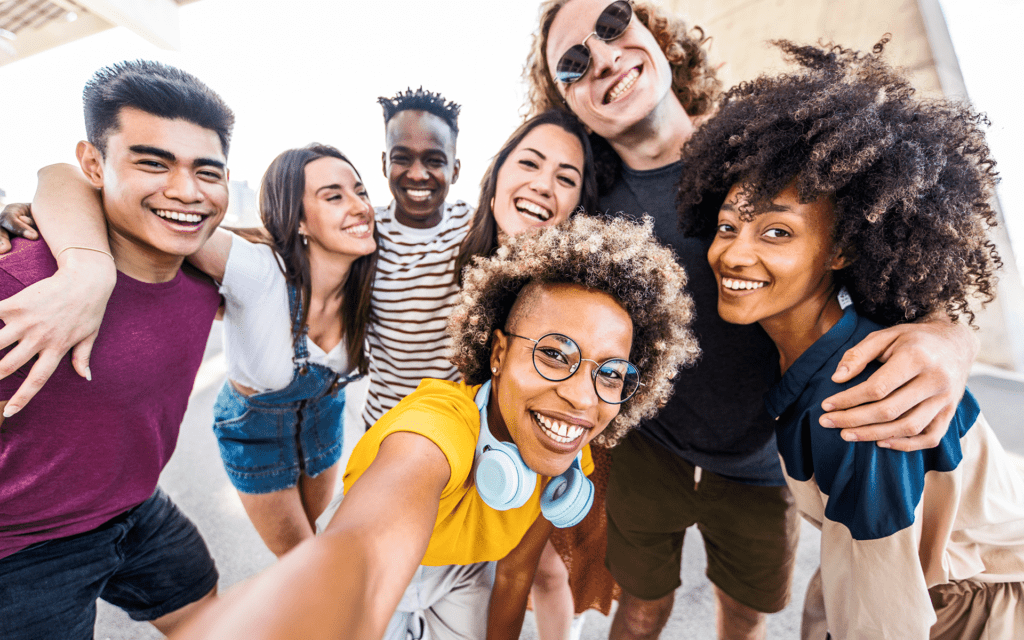 Photo of a diverse group of smiling teenagers crowding in for a group selfie.