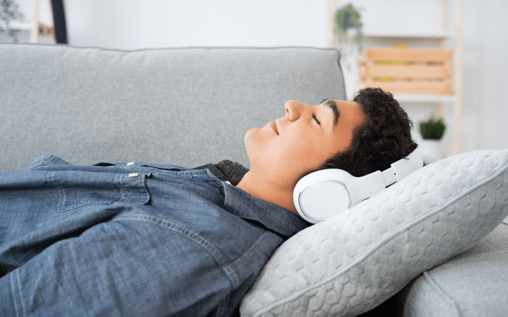 Photo of an Hispanic teenage boy relaxing on a couch wearing large white headphones.